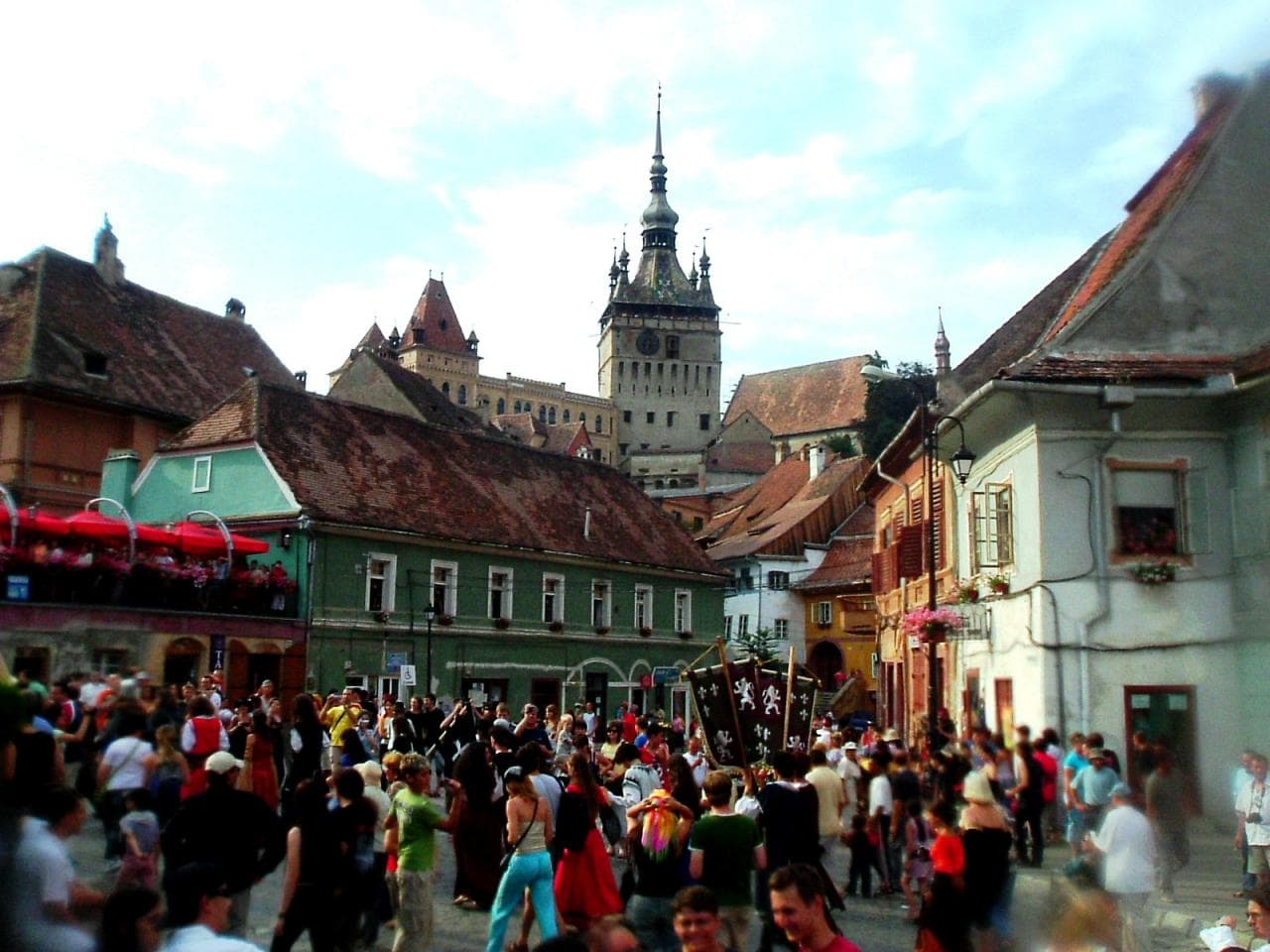 Crowds filling the streets of Sighișoara during the Medieval Festival, with the Clock Tower rising above the rooftops